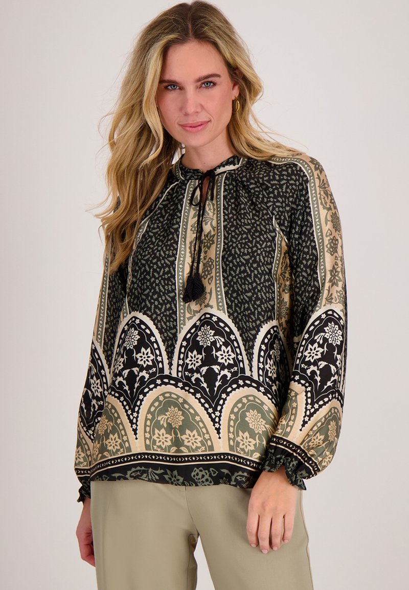 Blouse met een hoge halslijn, voorzien van zwarte en groene bloemenpatronen, elastische manchetten en een trekkoord met kwastjes.