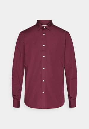 Chemise boutonnée à manches longues bordeaux en coton avec un col classique, des boutons blancs et un ourlet arrondi. Texture lisse, coupe ajustée.