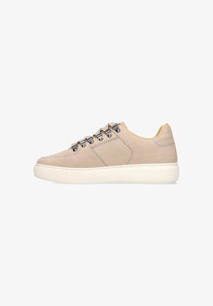 Beige lage sneaker met dikke witte zool, metalen veteroogjes en beige veters, zijaanzicht op een witte achtergrond.