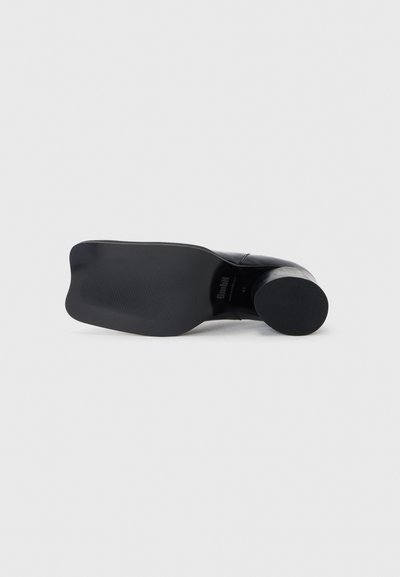 Black high-heeled shoe featuring a smooth leather upper, rounded toe, and textured rubber sole for grip. Size 41 indicated on the inside.