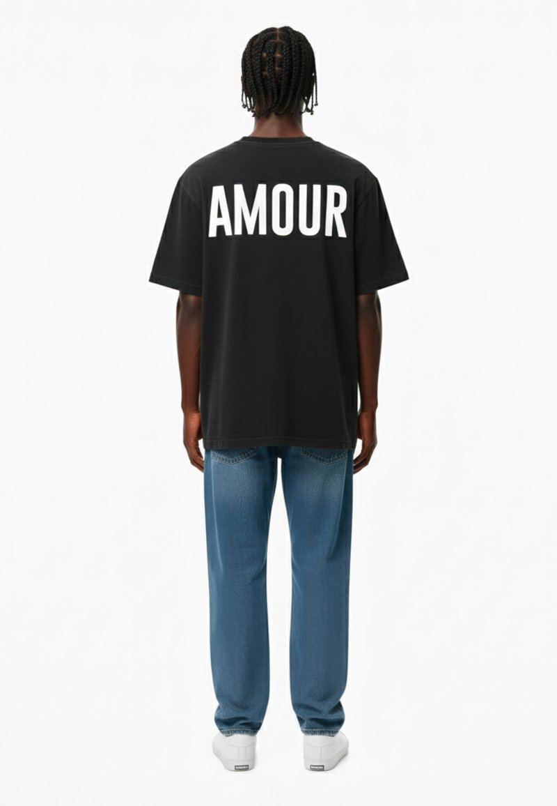 Juoda per didelė t-shirt su baltais užrašu "AMOUR" ant nugaros, derinama su šviesiai mėlynomis džinsinėmis kelnėmis ir baltomis sportbačiais. Paprastas dizainas su kasdiene išvaizda.
