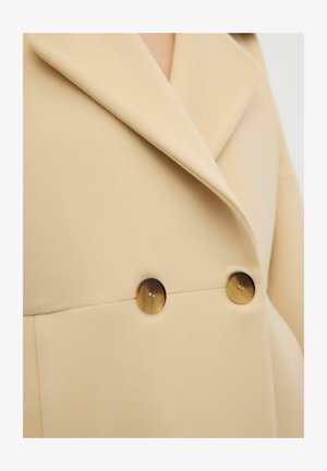 Cappotto in misto lana beige con collo a punta e due bottoni arrotondati in finta corna sul davanti, caratterizzato da una texture liscia e un design sartoriale.