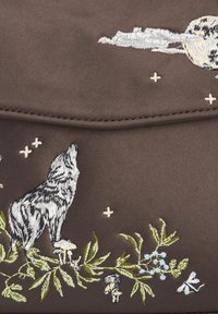 Sac en tissu brun avec une broderie complexe de loups blancs et noirs, accompagné de motifs de plantes, de champignons et d'étoiles.