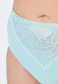 Mutandine in cotone azzurro chiaro con sovrapposizione di pizzo a motivo scallop. La vita è liscia, in contrasto con il pizzo testurizzato.
