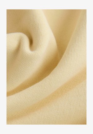 Svijetložuta pletiva s mekanom, glatkom teksturom i vidljivim finim rebrastim uzorcima, koji stvaraju blage nabore i lepršavi izgled.