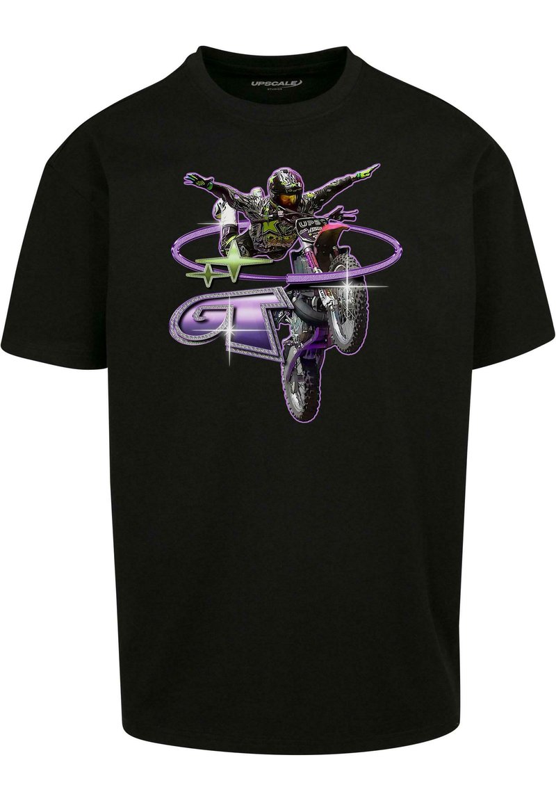 Sort bomulds T-shirt med grafisk tryk af en motocrosskører, der udfører et trick med lilla og grønne accenter, sat mod et livligt baggrund.