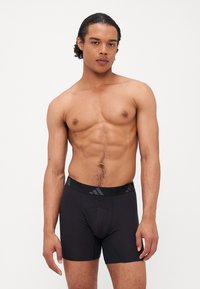 Boxers pretos com um tecido suave, cintura elástica com um padrão geométrico e um design ajustado para conforto e suporte.