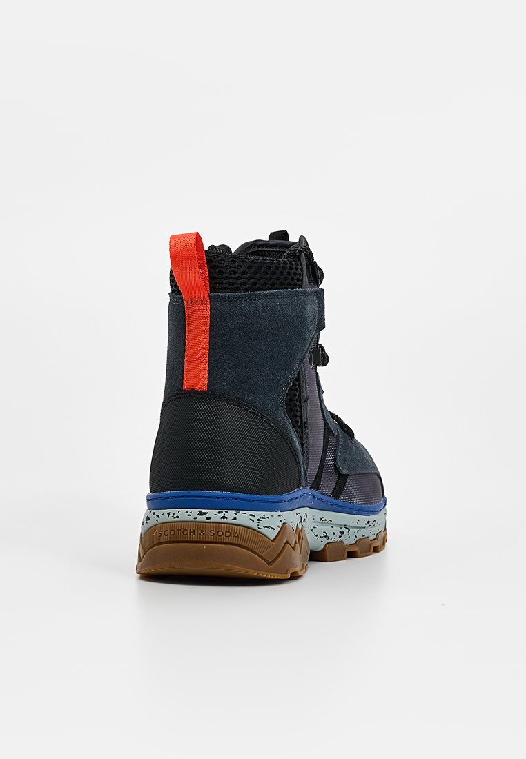 Stiefel mit einem dunkelblauen Obermaterial und Netzpaneelen, rotem Fersenloop, texturierter Gummisohle mit hellblauen Akzenten und einem robusten Design.