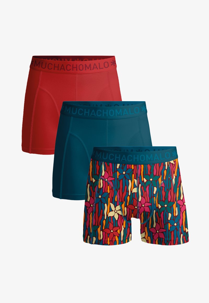 Trois boxers pour hommes alignés : rouge uni, bleu sarcelle uni, et motif floral multicolore avec ceinture bleue sarcelle portant le texte "MUCHACHOMALO".