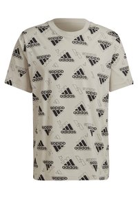 Beige t-paita, jossa on lyhyet hihat, All-over musta-valkoinen Adidas-logo-kuvio ja geometriset muodot.