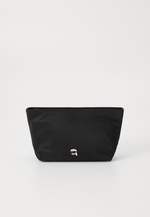 Black nylon pouch with a zippered top, slightly tapered design; features a minimalist silver logo detail at the front. Smooth texture.