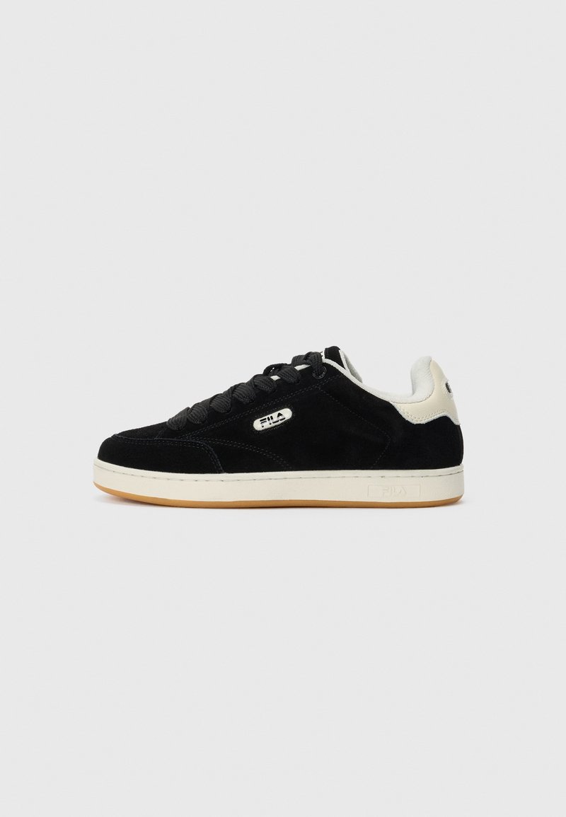 Baskets basses noires avec accent blanc au talon, lacets noirs, semelle blanche et logo FILA sur le côté et sur la languette du talon.