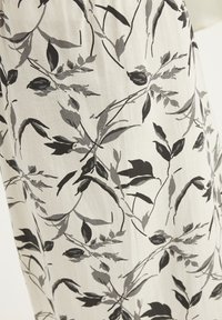 Tessuto leggero con un motivo floreale in scala di grigi. Il design include forme di foglie variabili e delicati accenti botanici.