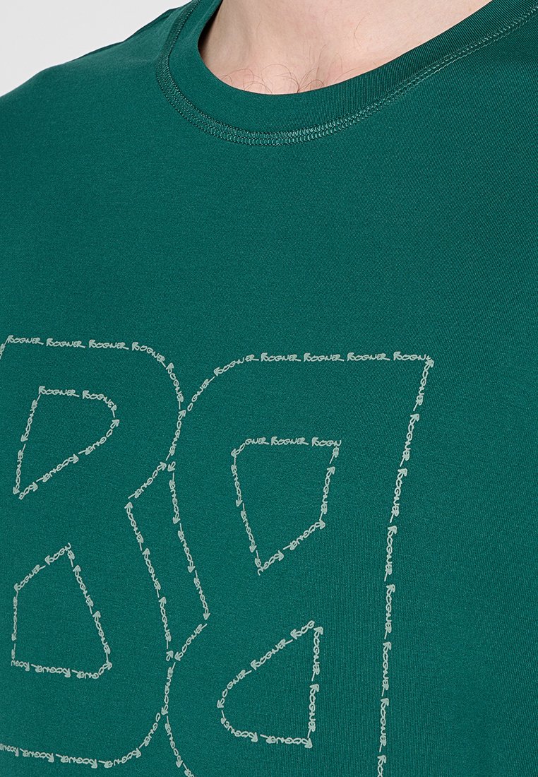 Grünes Baumwoll-T-Shirt mit einem großen, stilisierten Logodesign in Weiß, das sich aus wiederholendem Text in geometrischen Formen zusammensetzt. Runder Ausschnitt, kurze Ärmel.