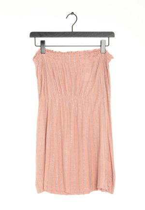 Robe pêche sans bretelles avec des rayures verticales argentées suspendue sur un cintre noir sur fond blanc.