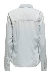 Camisa de mezclilla azul clara con mangas largas, cuello puntiagudo y costura en el yugo trasero. Presenta puños abotonados y un dobladillo curvado.