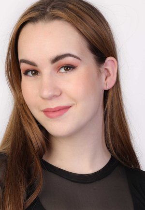 Modèle avec de longs cheveux bruns, portant de petites boucles d'oreilles en barres verticales dorées. Elle a un maquillage léger et naturel et porte un haut noir transparent.