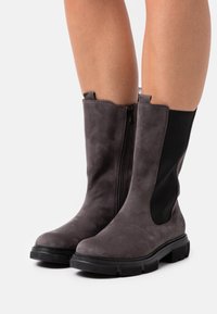 Grey ankle boots featuring a smooth suede finish, elastic side panels, and a side zipper. Black rubber soles with textured tread pattern.