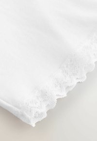 Fehér pamutszövet csipkével díszített szegéllyel. A csipke hullámos szélű és bonyolult mintázatú. Puha tapintású, sima megjelenésű.