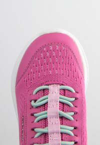Zapatilla deportiva rosa con parte superior de punto texturizado, suela blanca y sistema de cordones con patrón que presenta acentos azul claro.