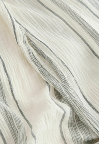 Leichtes, zerknittertes weißes Gewebe mit dünnen grauen Streifen. Weiche Textur und leichter Glanz, mit unregelmäßigen horizontalen Mustern.