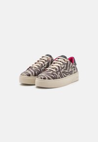 Joggesko med en teksturert zebra-mønstrete overdel i nyanser av brunt og krem, med beige lisser og en kontrasterende mørk hælflik.
