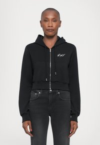 Felpa cropped nera realizzata in tessuto morbido; presenta una zip frontale, cappuccio e tasca frontale; include un ricamo bianco del logo sul petto.