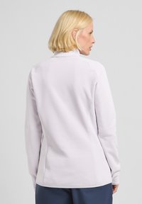 Maglietta sportiva a maniche lunghe di colore viola chiaro con colletto alto, design aderente, texture liscia e dettagli di cucitura sottili, mostrata da dietro.