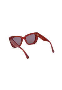 Gafas de sol rojo con forma de ojo de gato y lentes grises, con un acabado brillante, un diseño angular pronunciado y brazos curvados elegantes. Detalle de hardware dorado en la bisagra.