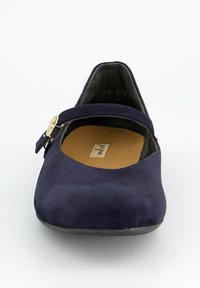 Zapato plano tipo Mary Jane de ante azul marino con una correa de hebilla dorada y plantilla color marrón claro sobre un fondo blanco.