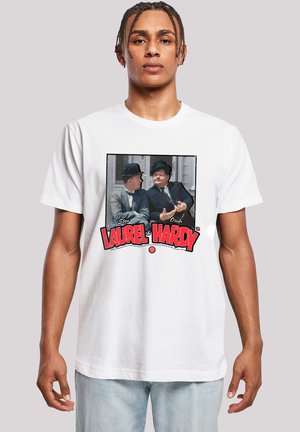 White cotton t-shirt featuring a graphic print of two characters in bowler hats, with "Laurel & Hardy" in bold red text below.