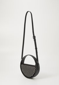 Black crossbody bag with round shape, studded front, adjustable strap, and zip closure. Smooth leather material.