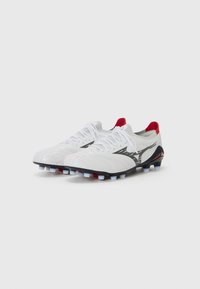 Witte voetbal schoenen met een gestructureerd oppervlak, zwarte accenten, rode details bij de hak en meerdere witte en rode noppen op de zool.