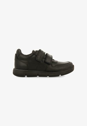 Zapatillas para niños negras con una parte superior de cuero liso, cierre de tiras de Velcro, cuello acolchado y suela de goma texturizada.