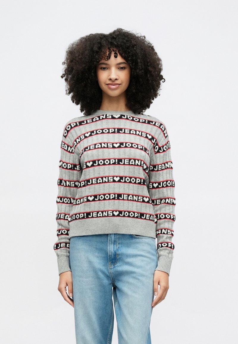 Γκρι πλεχτό πουλόβερ με έντονο επαναλαμβανόμενο σχέδιο κειμένου "JOOP! JEANS" σε μαύρο και κόκκινο. Πλεκτές μανσέτες και τελείωμα με ριμπ ύφανση, άνετη εφαρμογή. Ανοιχτόχρωμο τζιν παντελόνι.
