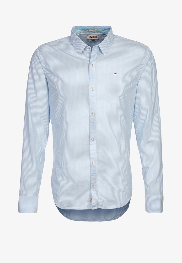 Ljusblå skjorta med lång ärm och knappar, med vita vertikala ränder. Har en klassisk krage och en diskret logotyp på bröstet. Slät tygstruktur.