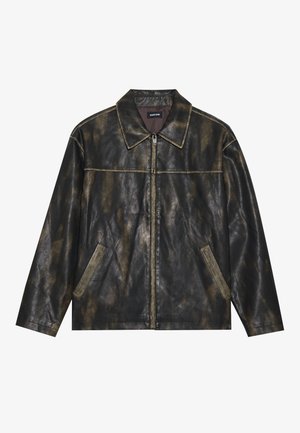Giacca in pelle nera e oro opaco con una consistenza liscia, colletto a punta, chiusura con zip e due tasche laterali angolate.