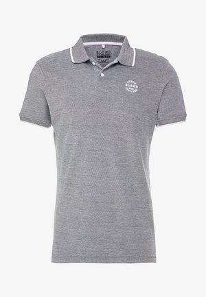 Szürke póló, texturált anyagból, kontrasztos szegélyű gallérral, három gombos kivágással és kör alakú logóval a mellkasán.