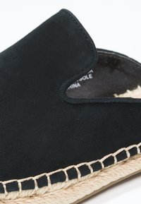 Chaussure noire en suédine à enfiler avec un dessus arrondi, dotée d'une semelle en jute et d'accents cousus le long du bord.