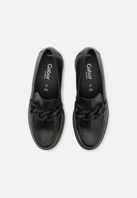 Zapatos de cuero negro sin cordones con un adorno de cadena a lo largo del empeine, puntera redondeada y plantilla acolchada. Nombre de la marca Gabor visible en el interior.