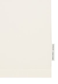 Tessuto di colore crema con una superficie liscia e un bordo ripiegato. Presenta un'etichetta laterale piccola con la scritta "COUCH COUTURE" in caratteri neri.