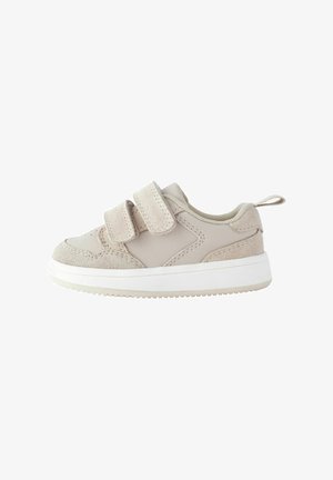 Adidași bej cu două curele Velcro, superior din suede și piele sintetică, talpă din cauciuc alb și o bandă de prindere la călcâi.