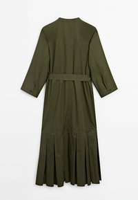 Longue robe vert olive à manches longues, poignets boutonnés, ceinture à la taille et détails plissés en bas, vue de dos.