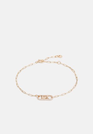 Jemná zlatá retiazková náramok s obdĺžnikovým príveskom zdobeným malými priehľadnými kamienkami a vygravírovanými iniciálmi "MK".