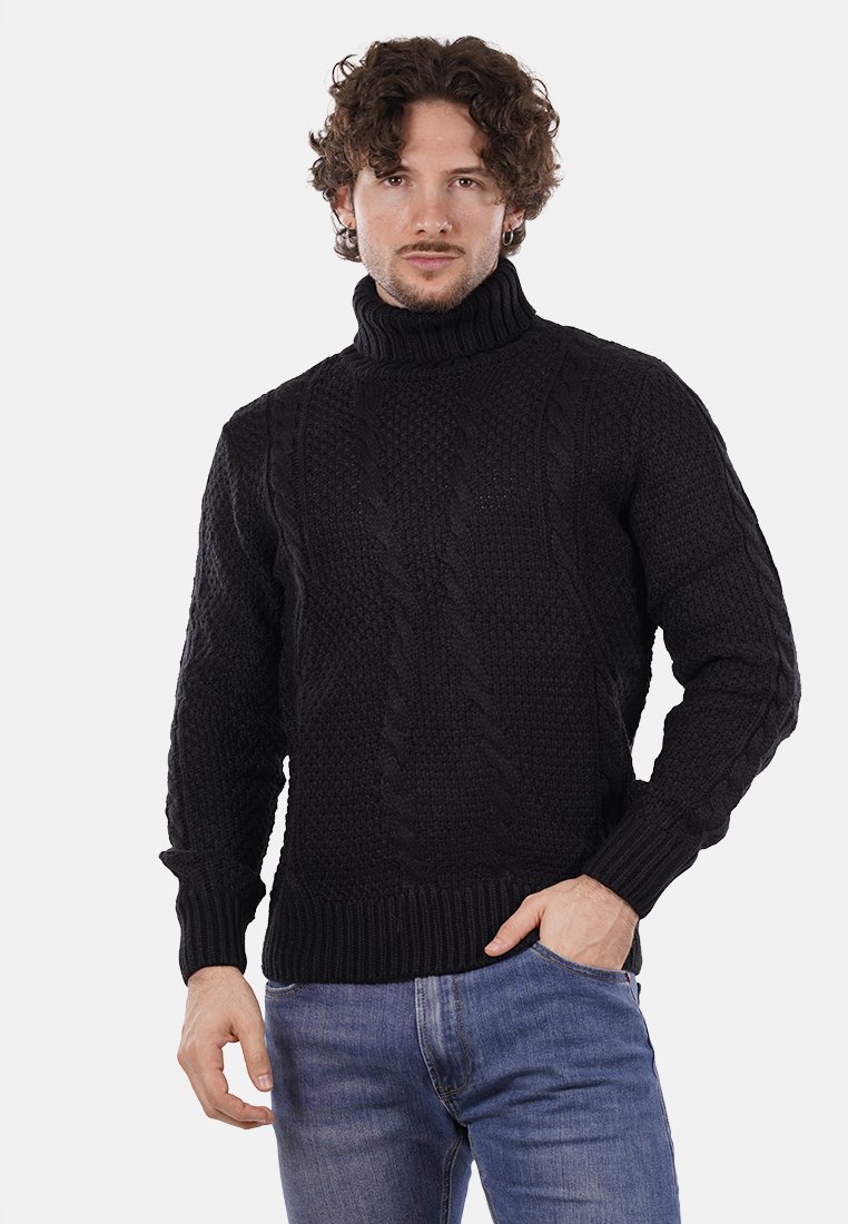 Maglione nero a collo alto lavorato a maglia con design a trecce testurizzate, polsini e orlo a coste, abbinato a jeans blu.