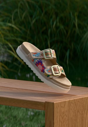 Sandale à plateforme beige avec des brides en textile tissé coloré et deux boucles dorées. Semelle en caoutchouc blanche avec un dessin texturé pour l'adhérence.