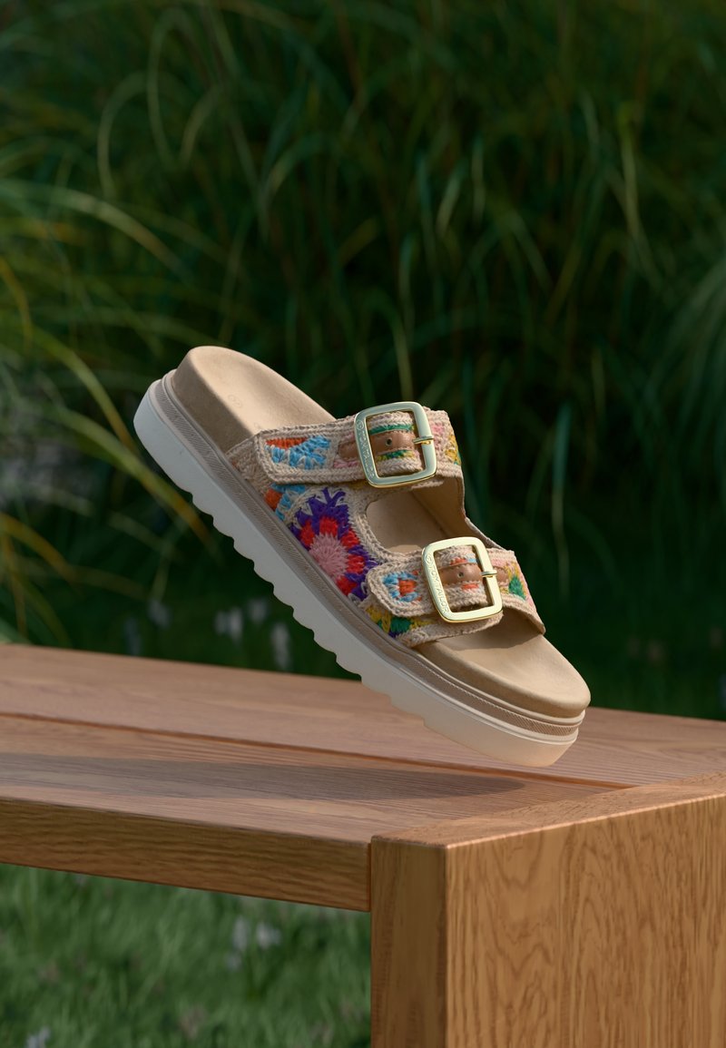Sandale à plateforme beige avec des brides en textile tissé coloré et deux boucles dorées. Semelle en caoutchouc blanche avec un dessin texturé pour l'adhérence.
