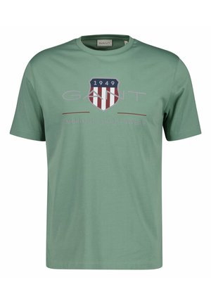 Groene GANT T-shirt met korte mouwen en een schildlogo met "1949" en rode, witte strepen en de tekst "American Sportswear" op de voorkant.