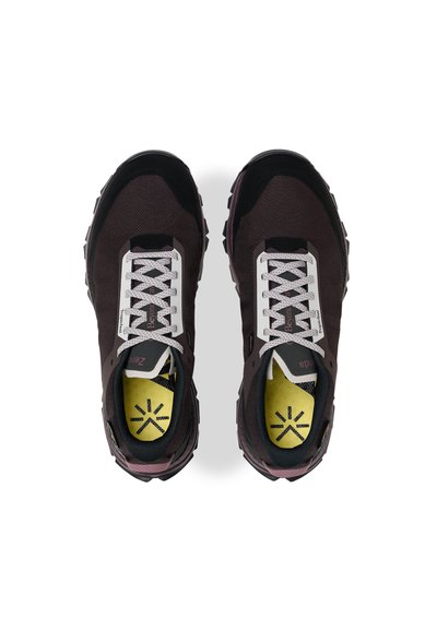 Une paire de chaussures de trail noires et violettes avec des lacets blancs et des semelles intérieures jaunes arborant des motifs d'étoiles noires, vue de dessus.