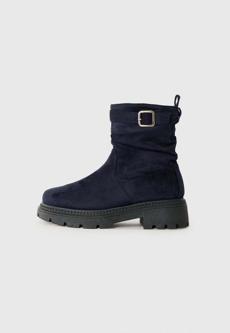 Mørkeblå suede ankelstøvler med et slouchy design, sort kraftig sål og en sølvspændeaccent på det justerbare bånd.